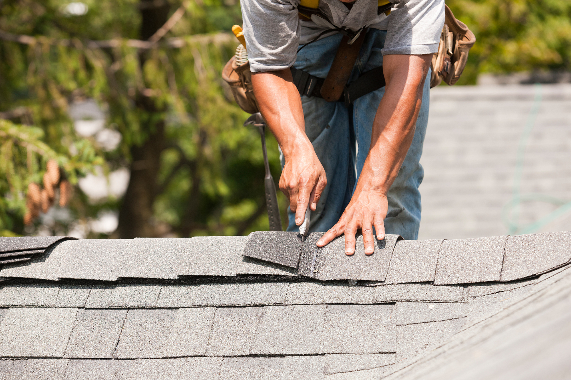 Roof replacement - roofer cutting a shingle